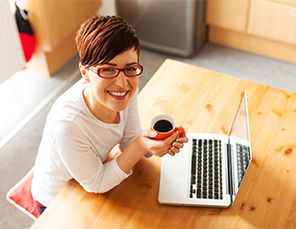 Woman drinking coffee in front of laptop